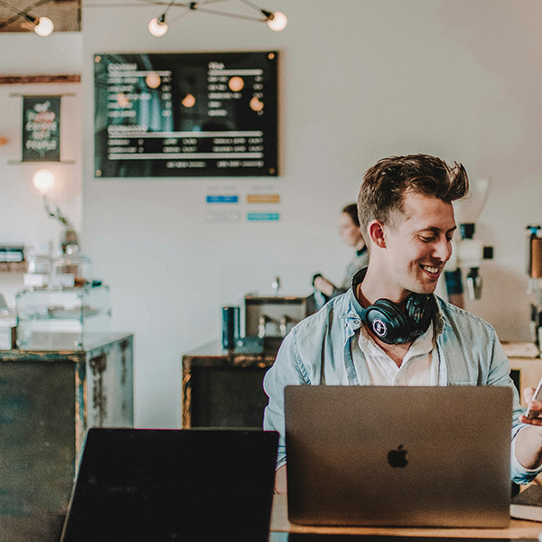 600x600px - Man smiling on phone and laptop