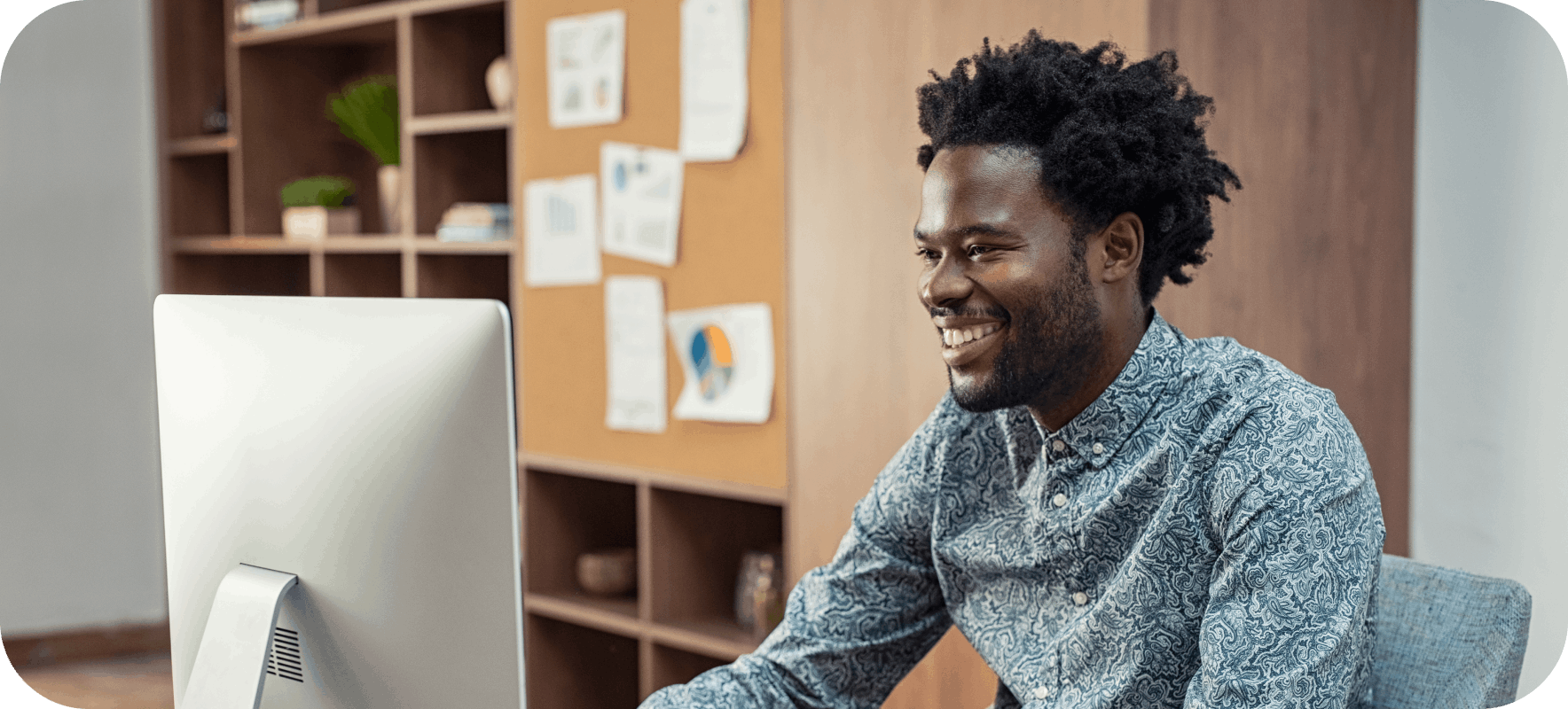 Smiling man at his desk looking at computer monitor