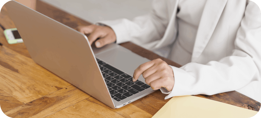 Woman in white suit using laptop on desk