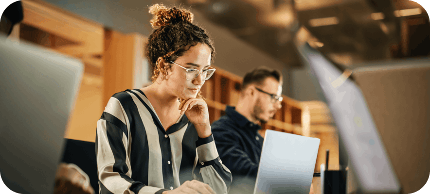 Woman looking at her laptop screen in a busy office